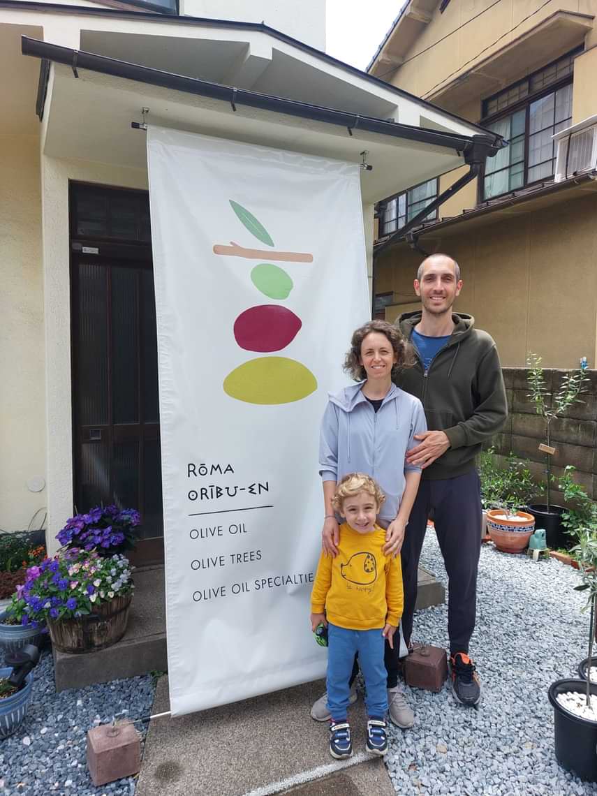 オリーブオイル専門店「ローマ・オリーブ園」の入り口前で、妻と息子と抱き合っているガブリエレさんの家族写真
